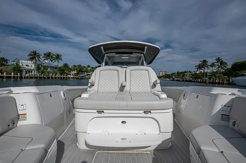 Slide: The Image of 2023 Intrepid 427 Nomad SE boat interior with luxurious seating, docked by palm trees. - 13