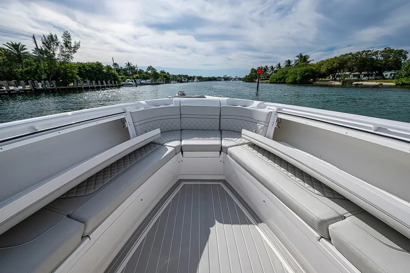 Slide: The Image of 2023 Intrepid 427 Nomad SE boat interior with luxurious seating on a scenic waterway. - 15