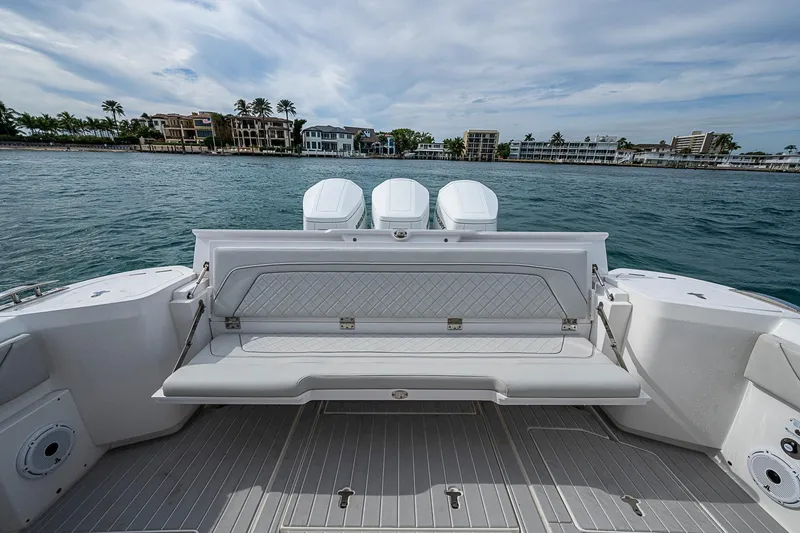 Slide: The Image of 2023 Intrepid 427 Nomad SE boat with luxurious seating, docked near waterfront homes. - 22