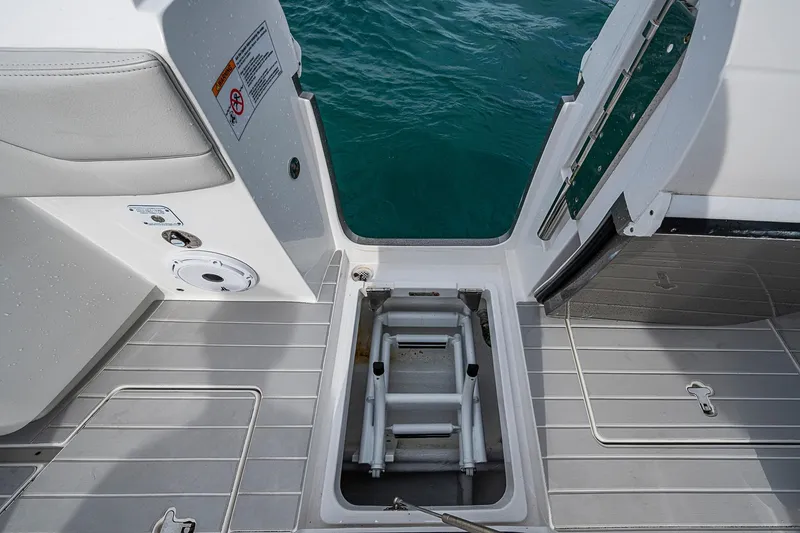 Slide: The Image of 2023 Intrepid 427 Nomad SE boat with open hatch and ladder, near water. - 27