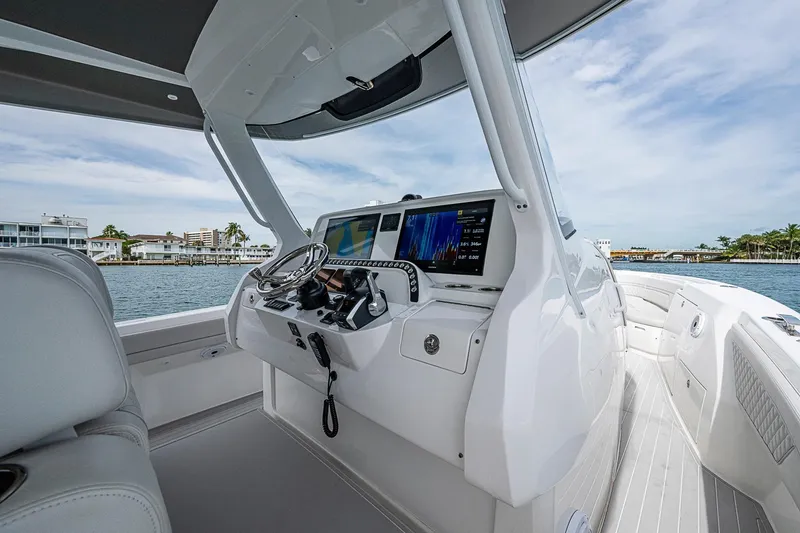 Slide: The Image of 2023 Intrepid 427 Nomad SE boat cockpit with advanced navigation system, docked by waterfront homes. - 50