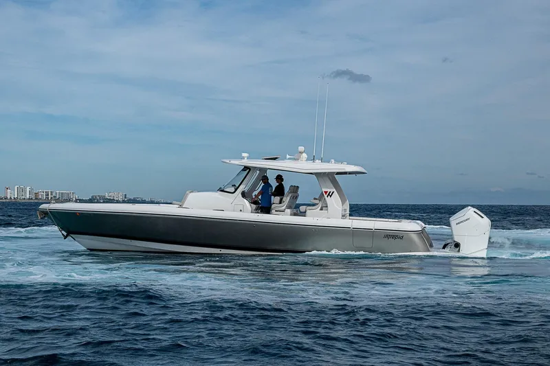 Slide: The Image of 2023 Intrepid 427 Nomad SE boat cruising on open water, city skyline in background. - 70