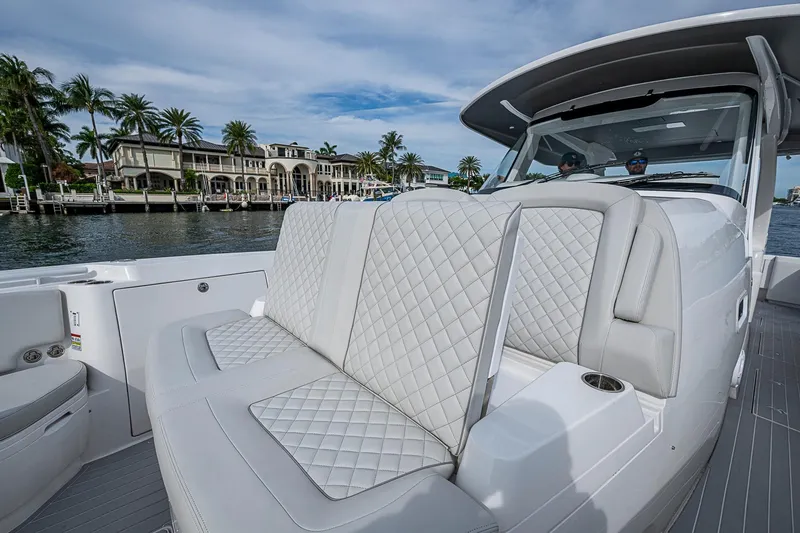 Slide: The Image of 2023 Intrepid 427 Nomad SE luxury boat with quilted seating, cruising near waterfront homes. - 8