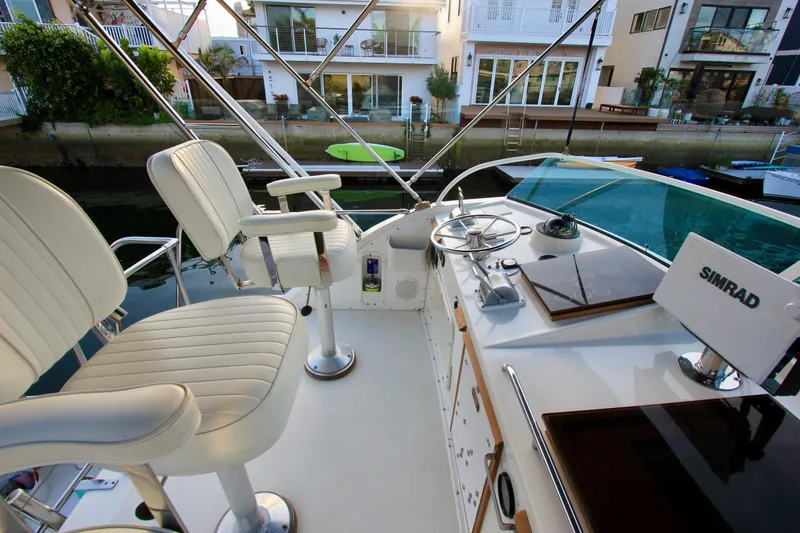 Slide: The Image of 1980 Bertram 35 Flybridge helm with white seats and Simrad navigation system. - 21