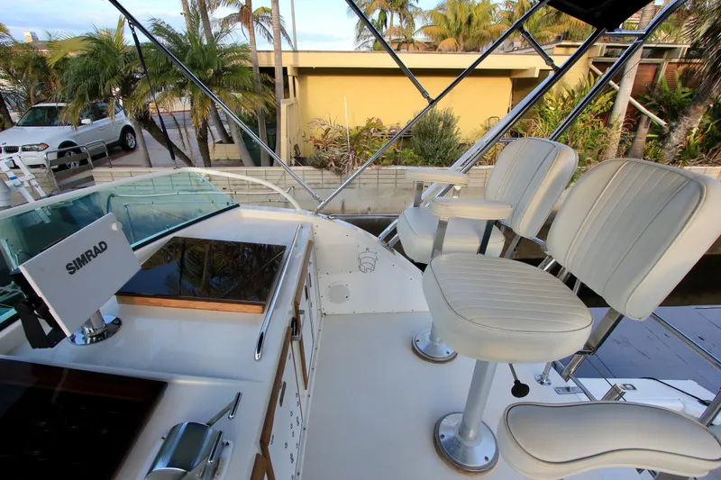 Slide: The Image of 1980 Bertram 35 Flybridge with white seating and Simrad navigation system. - 22