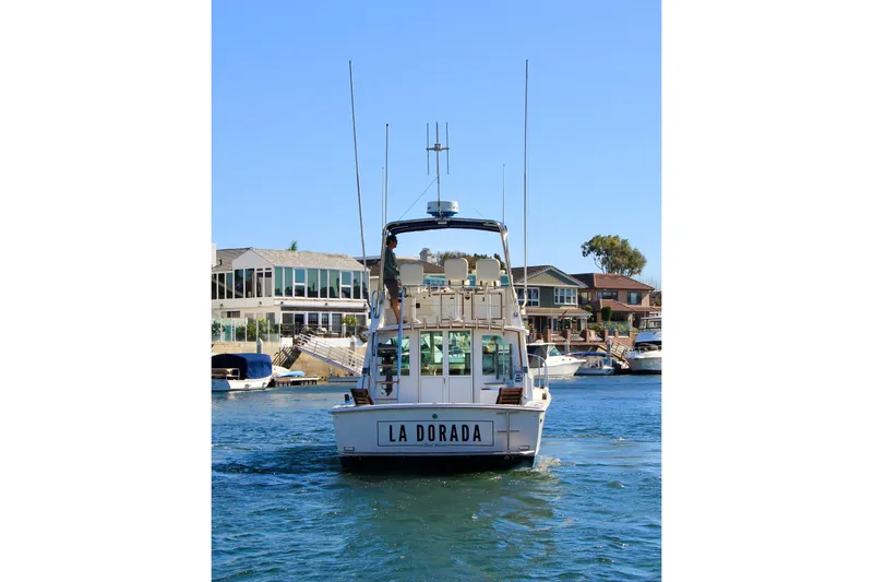 Slide: The Image of 1980 Bertram 35 Flybridge boat "La Dorada" cruising in a scenic waterfront area. - 7