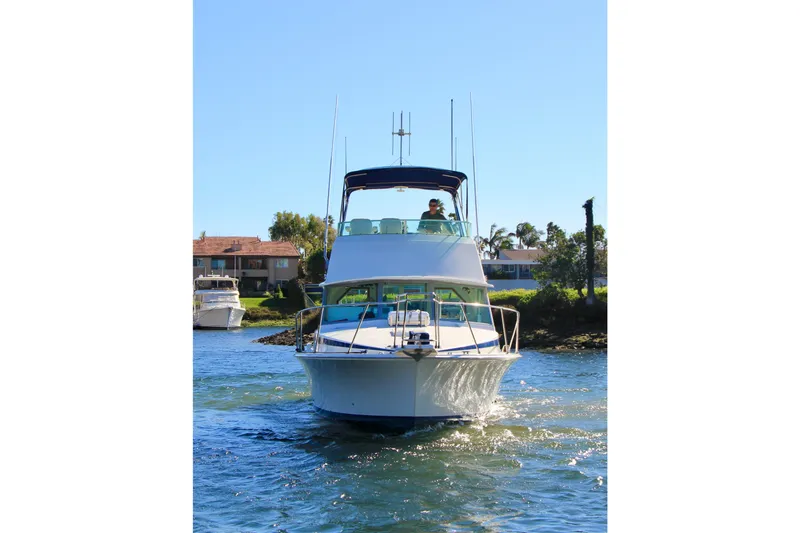 Slide: The Image of 1980 Bertram 35 Flybridge cruising on a sunny day near waterfront homes. - 8