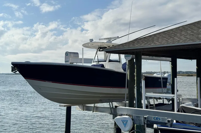 Slide: The Image of 2022 Regulator 34 boat docked on a lift by the water under a cloudy sky. - 2