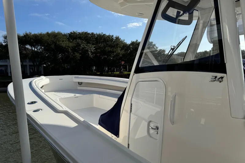 Slide: The Image of 2022 Regulator 34 boat with sleek design, docked near trees under blue sky. - 7