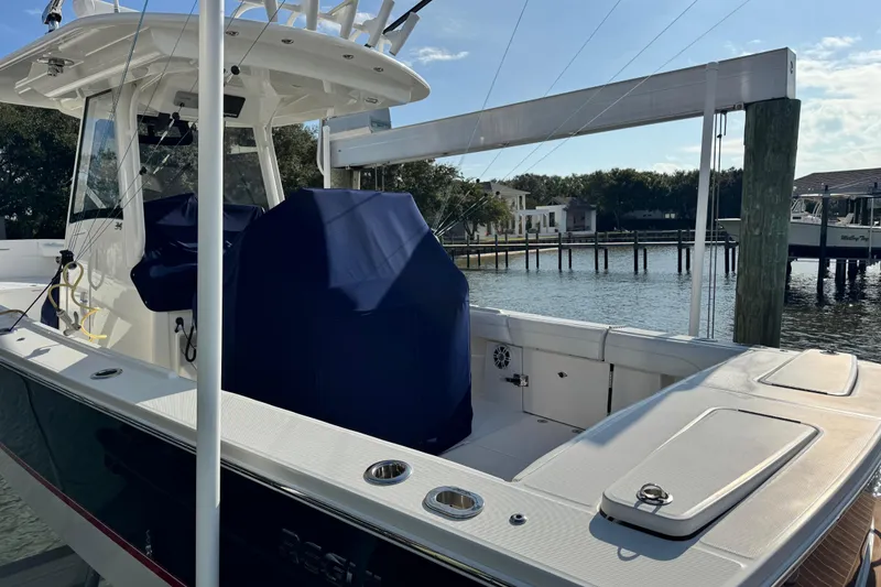 Slide: The Image of 2022 Regulator 34 boat docked by waterfront homes, featuring covered seating and fishing equipment. - 8