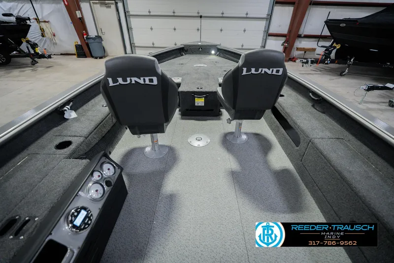Slide: The Image of 2026 Lund 1875 Pro Guide boat interior with dual seats in a showroom. - 12