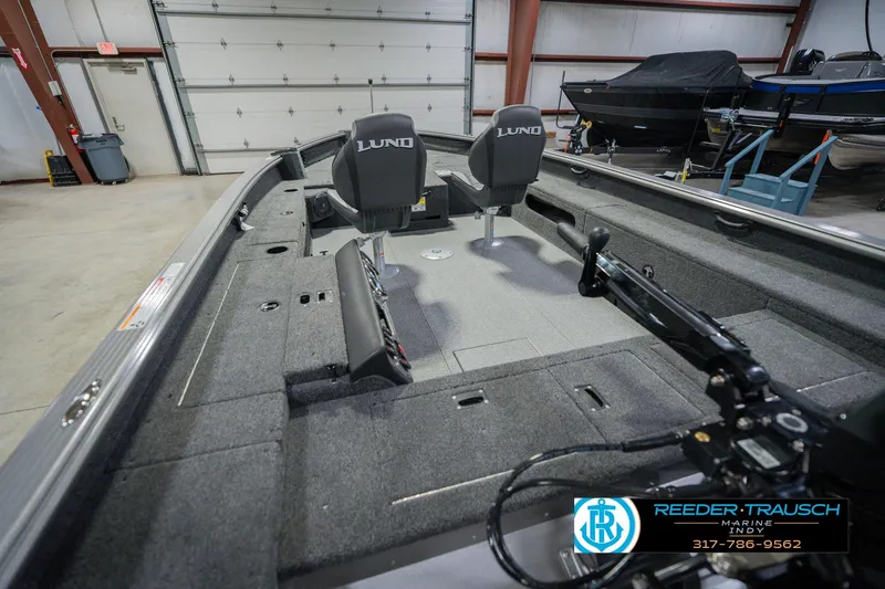 Slide: The Image of 2026 Lund 1875 Pro Guide boat interior with seating and equipment in a showroom. - 13