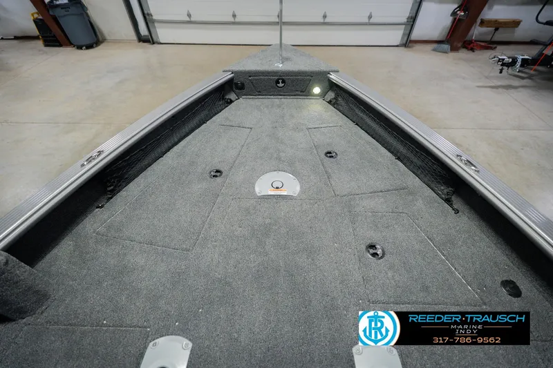 Slide: The Image of 2026 Lund 1875 Pro Guide boat interior with carpeted deck in a garage setting. - 14