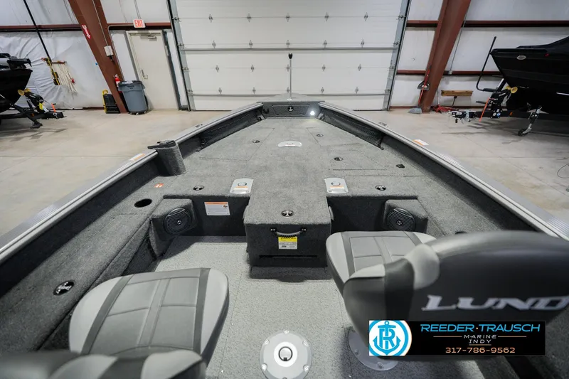 Slide: The Image of 2026 Lund 1875 Pro Guide fishing boat interior in a showroom, featuring seating and storage. - 15