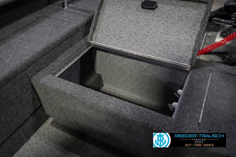 Slide: The Image of 2026 Lund 1875 Pro Guide boat storage compartment, open lid, carpeted interior. - 21