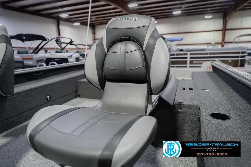 Slide: The Image of 2026 Lund 1875 Pro Guide boat interior with sleek, modern seating in showroom. - 36