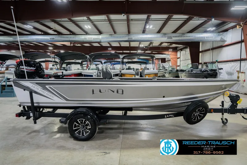Slide: The Image of 2026 Lund 1875 Pro Guide boat in showroom, side view with trailer. - 4