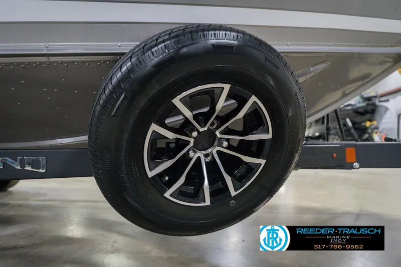Slide: The Image of 2026 Lund 1875 Pro Guide boat trailer wheel, featuring sleek black and silver alloy design. - 53