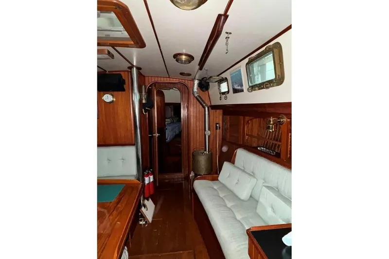 Slide: The Image of Interior of 1986 Crealock 40 sailboat with wood paneling and cozy seating area. - 13