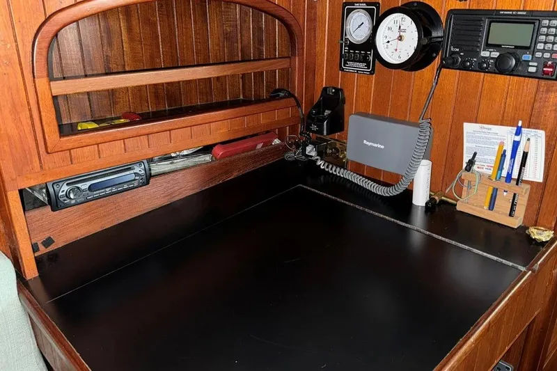 Slide: The Image of Navigation station on 1986 Crealock 40 sailboat with radio, clock, and writing tools. - 14