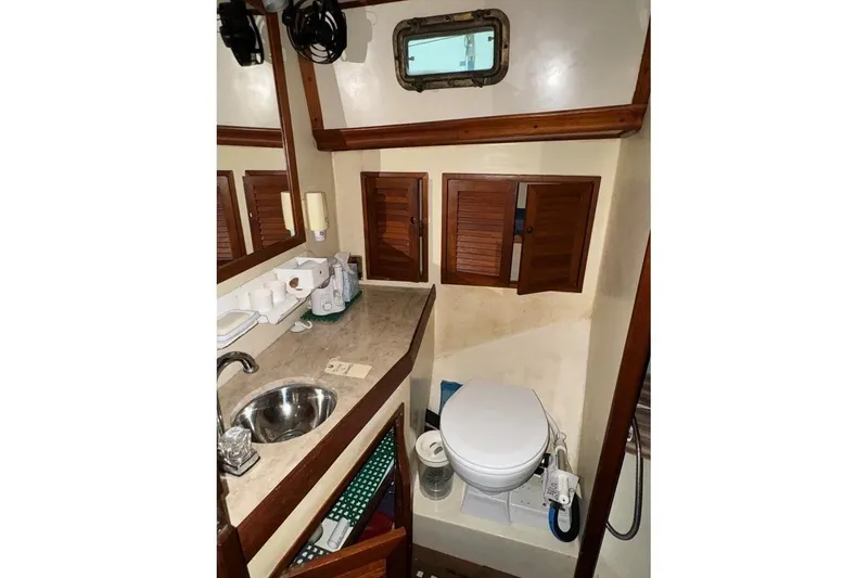 Slide: The Image of 1986 Crealock 40 yacht bathroom with sink, toilet, and wooden cabinets. - 22