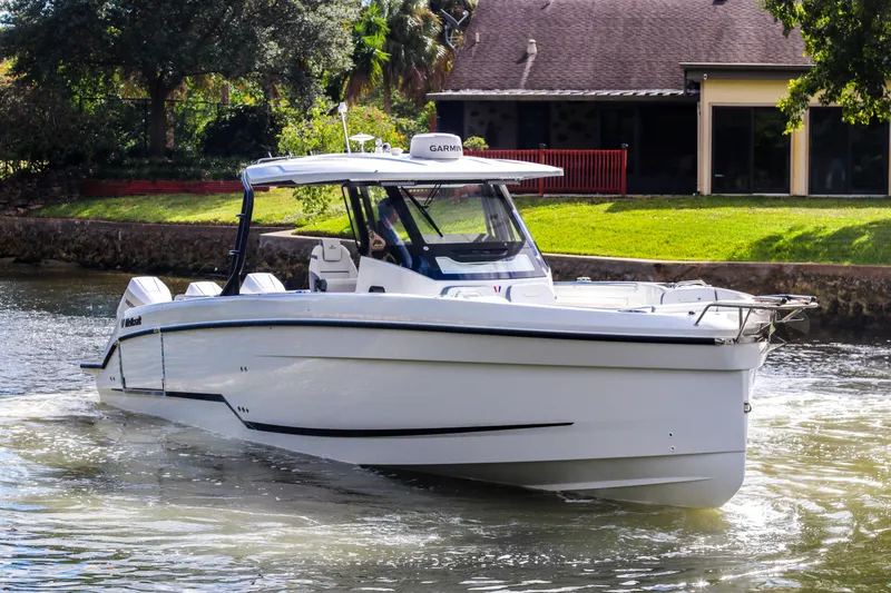 Slide: The Image of 2026 Wellcraft 38 T-Top boat cruising on a sunny day near a waterfront home. - 2