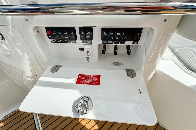 Slide: The Image of Control panel of 2026 Wellcraft 38 T-Top boat with switches and warning label. - 16