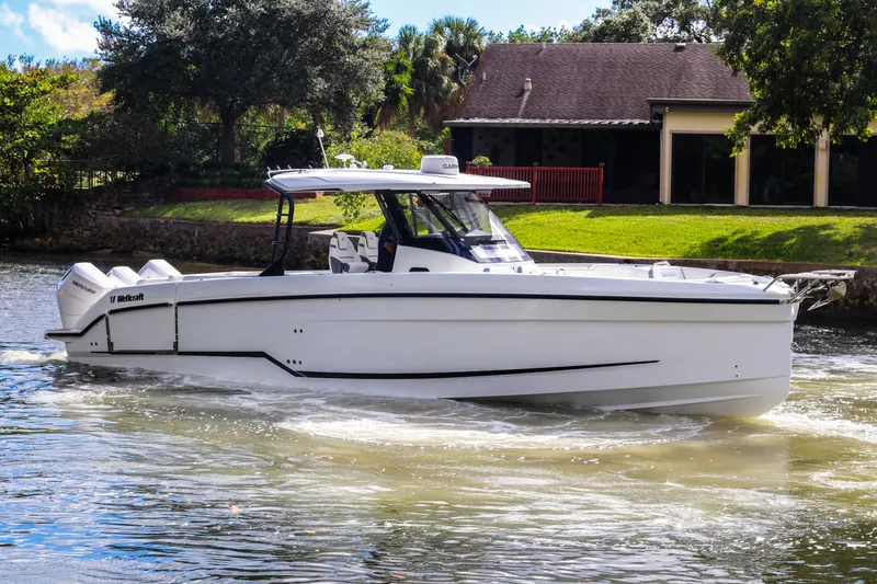 Slide: The Image of 2026 Wellcraft 38 T-Top boat cruising on a sunny day near a house. - 3