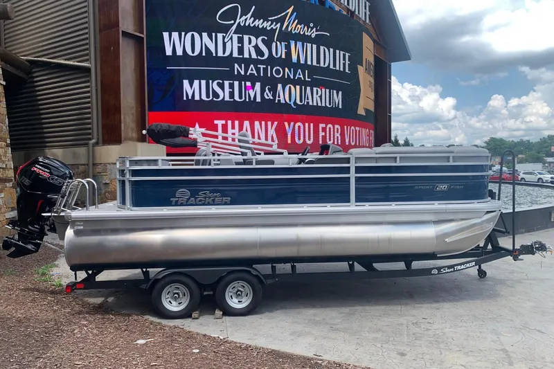 The Image of 2026 Sun Tracker SportFish 20 DLX pontoon boat on trailer, parked outside museum. - 0
