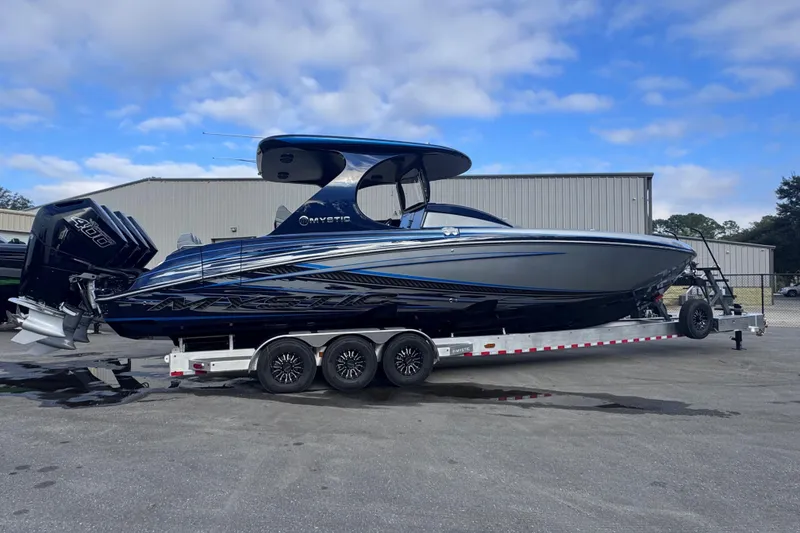 The Image of 2026 Mystic Powerboats M3800 on trailer, sleek design, blue and black color scheme. - 1