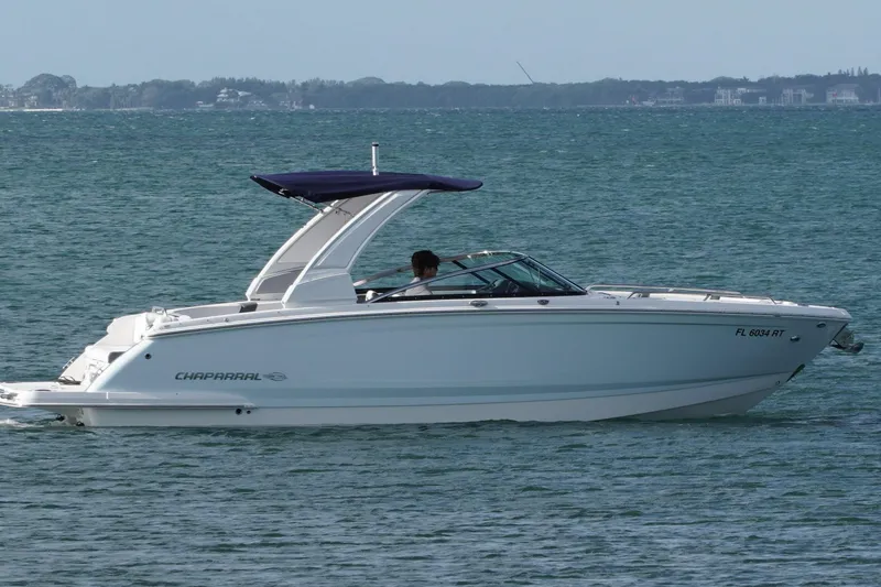 Slide: The Image of 2019 Chaparral 227 SSX boat cruising on open water with a blue canopy. - 1