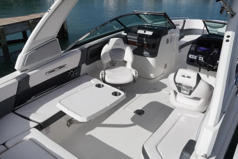 Slide: The Image of 2019 Chaparral 227 SSX boat interior with seating and table, docked by water. - 11