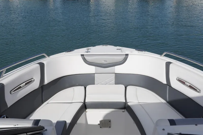 Slide: The Image of 2019 Chaparral 227 SSX boat interior with white and gray seating, docked on calm water. - 16
