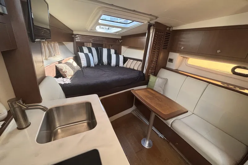 Slide: The Image of Interior of 2017 Sea Ray 310 Sundancer with cozy seating, bed, and kitchenette. - 11