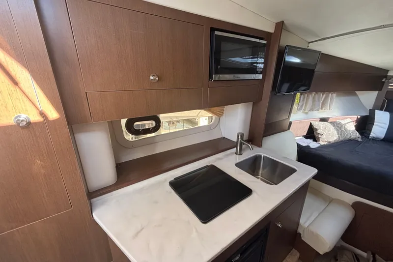 Slide: The Image of 2017 Sea Ray 310 Sundancer interior with kitchenette, sink, and bed. - 12