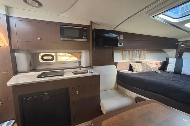 Slide: The Image of 2017 Sea Ray 310 Sundancer interior with kitchenette, bed, and seating area. - 14