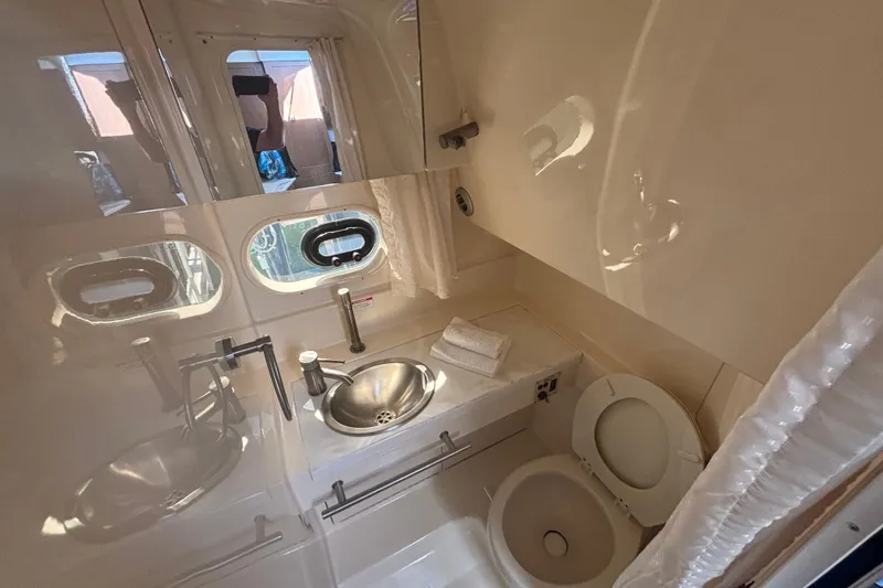 Slide: The Image of 2017 Sea Ray 310 Sundancer bathroom with sink, toilet, and porthole windows. - 16