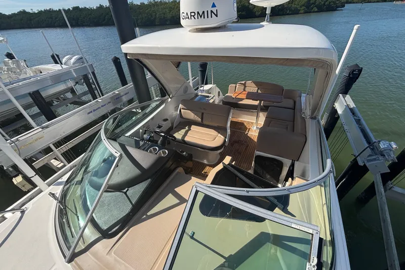 Slide: The Image of 2017 Sea Ray 310 Sundancer boat with spacious seating and Garmin navigation, docked by the water. - 2