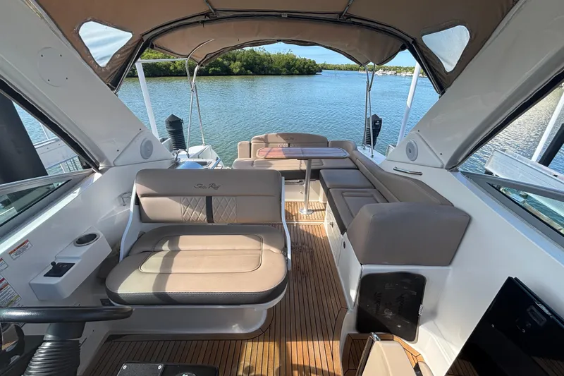 Slide: The Image of 2017 Sea Ray 310 Sundancer boat interior with seating and table, overlooking serene water. - 6