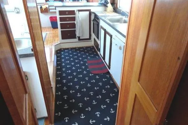 Slide: The Image of 1985 Pearson 43 Trawler kitchen with anchor-patterned carpet and wooden cabinetry. - 11