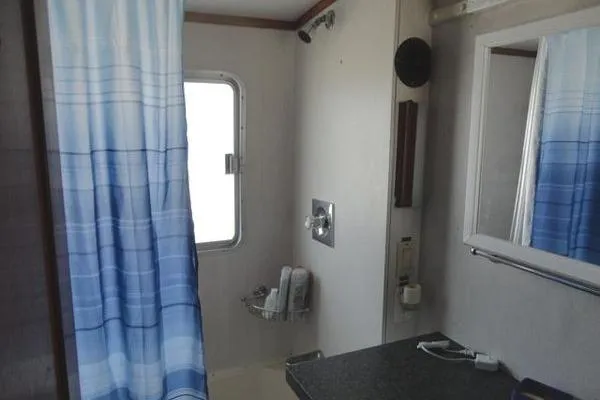 Slide: The Image of Bathroom interior of 1985 Pearson 43 Trawler with blue shower curtain and window. - 14