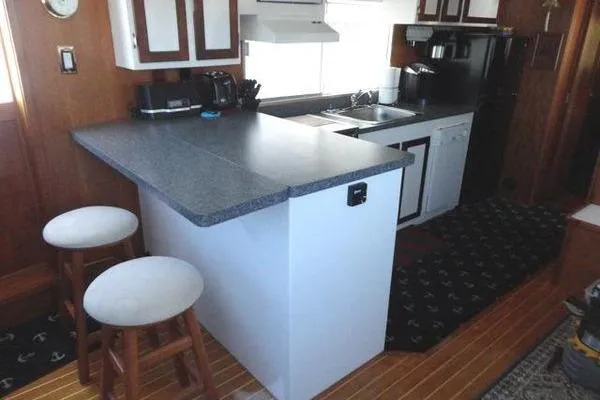 Slide: The Image of 1985 Pearson 43 Trawler kitchen with bar stools, countertop, and appliances. - 21