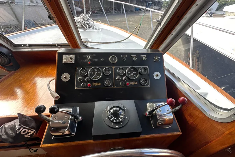 Slide: The Image of 1985 Pearson 43 Trawler helm with gauges, controls, and compass in a wooden cabin. - 25