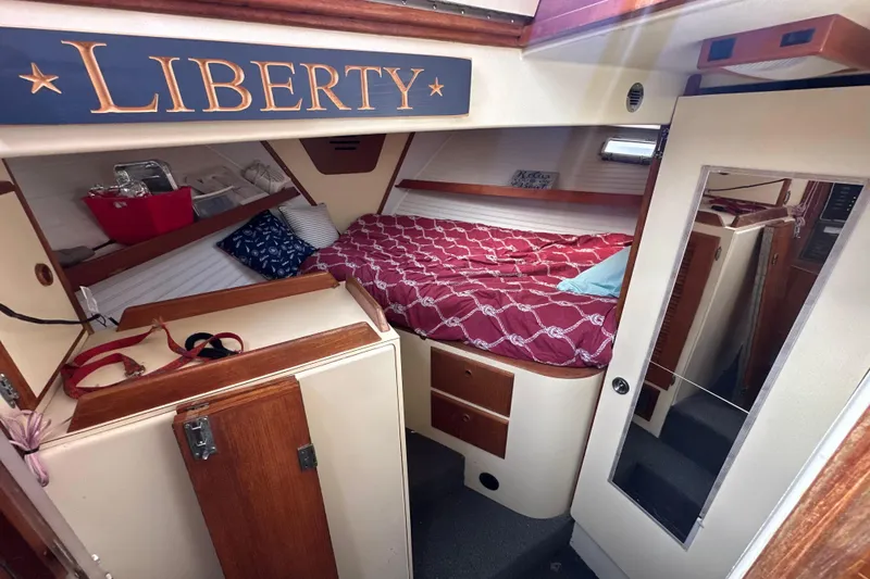 Slide: The Image of Cozy cabin interior of 1985 Pearson 43 Trawler with red bedding and wooden accents. - 26