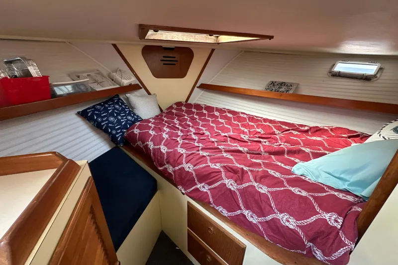 Slide: The Image of Cozy cabin interior of 1985 Pearson 43 Trawler with red bedding and nautical decor. - 27