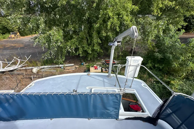 Slide: The Image of 1985 Pearson 43 Trawler deck view with crane, surrounded by trees and equipment. - 34