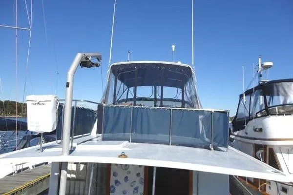 Slide: The Image of 1985 Pearson 43 Trawler boat docked, featuring blue canopy and clear sky background. - 36