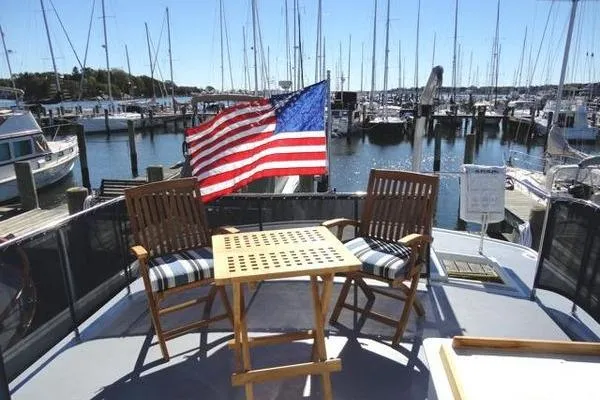 Slide: The Image of 1985 Pearson 43 Trawler deck with chairs, table, and American flag at marina. - 38