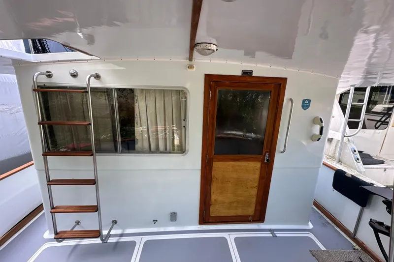 Slide: The Image of 1985 Pearson 43 Trawler aft deck with ladder, window, and wooden door. - 5