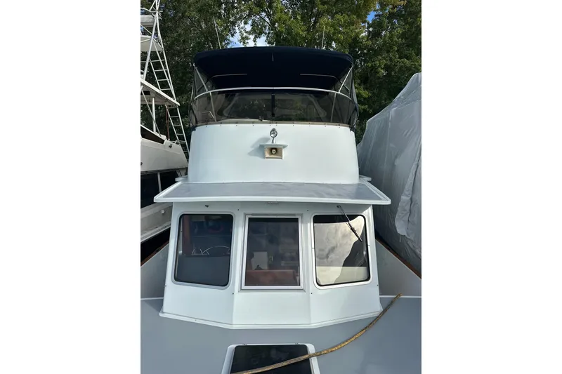 Slide: The Image of 1985 Pearson 43 Trawler with blue canopy, docked among trees. - 50